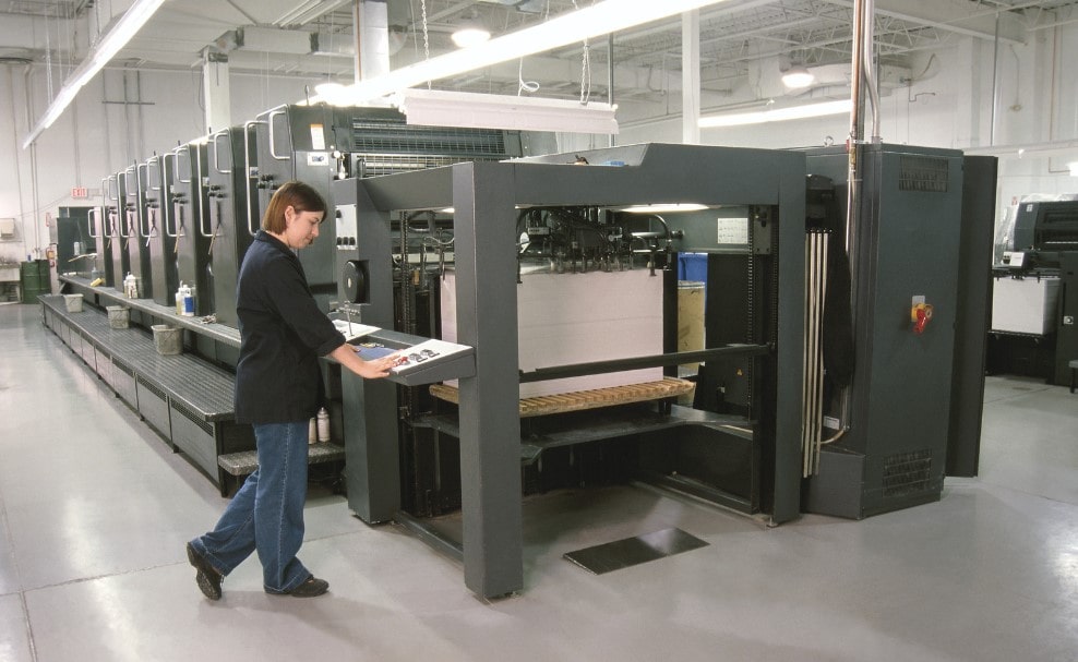 A worker operates a commercial printing machine, this will create designs for businesses quickly.